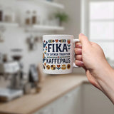 A hand holds the Swedish Gift Store’s Mug: Swedish Fika Traditions Wraparound Ceramic Mug (11 oz), featuring colorful patterns and the text "FIKA EN SVENSK TRADITION KAFFEPAUS," in a bright kitchen with a blurred background.