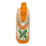 Orange Swedish Dala horse with green and white floral patterns on its body, made of pine wood, shown from above on a white background.