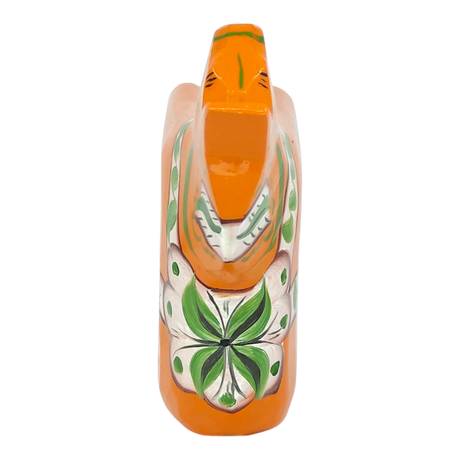 Orange Swedish Dala horse with green and white floral patterns on its body, made of pine wood, shown from above on a white background.