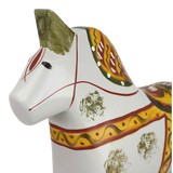 White Swedish Dala horse with carved details, decorated with red, green, and yellow painted patterns on the body and mane.