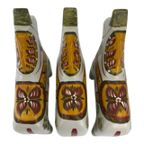Three white hand carved wooden horses with orange, yellow, and red floral patterns on their backs, in the Swedish Dala horse style.