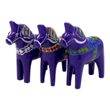 Three purple Dala Horse figurines made of Swedish pine wood, each hand-painted with colorful Scandinavian patterns, displayed side by side.