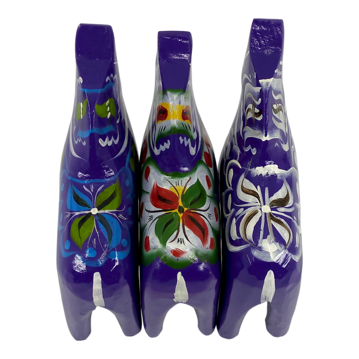 Three purple Swedish Dala horse figurines, hand-painted with colorful floral patterns on their backs, arranged side by side on a white background, viewed from above.