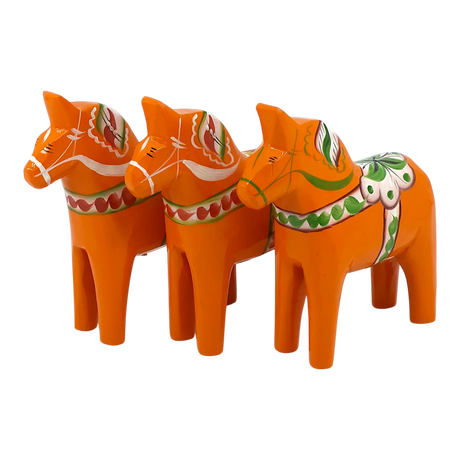 Three orange Swedish Dala horses with traditional painted patterns, arranged in a row on a white background.