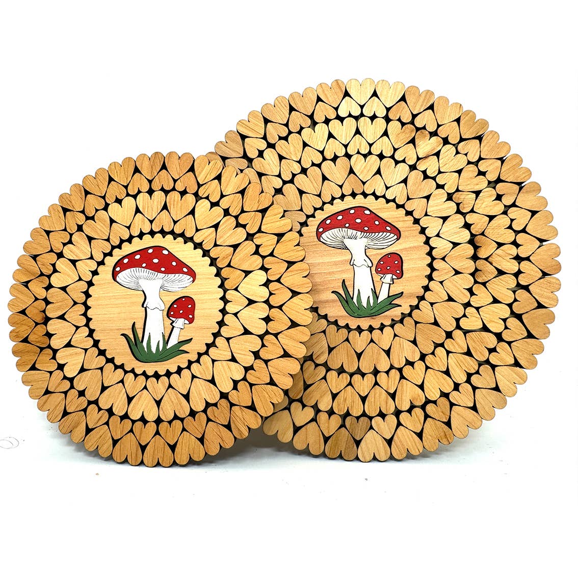 The handmade circular wooden trivets from Estonia feature a leaf pattern and central design of red mushrooms with white spots, adding charm to any kitchen décor. Known as Trivet: Mushroom Wooden Trivets for Hot Dishes with Laser Cut Hearts.