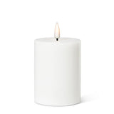 The 4" LED Pillar Candle in white features a cylindrical shape with a realistic LED flame that flickers gently at the top, providing a soothing glow for up to 150 hours.