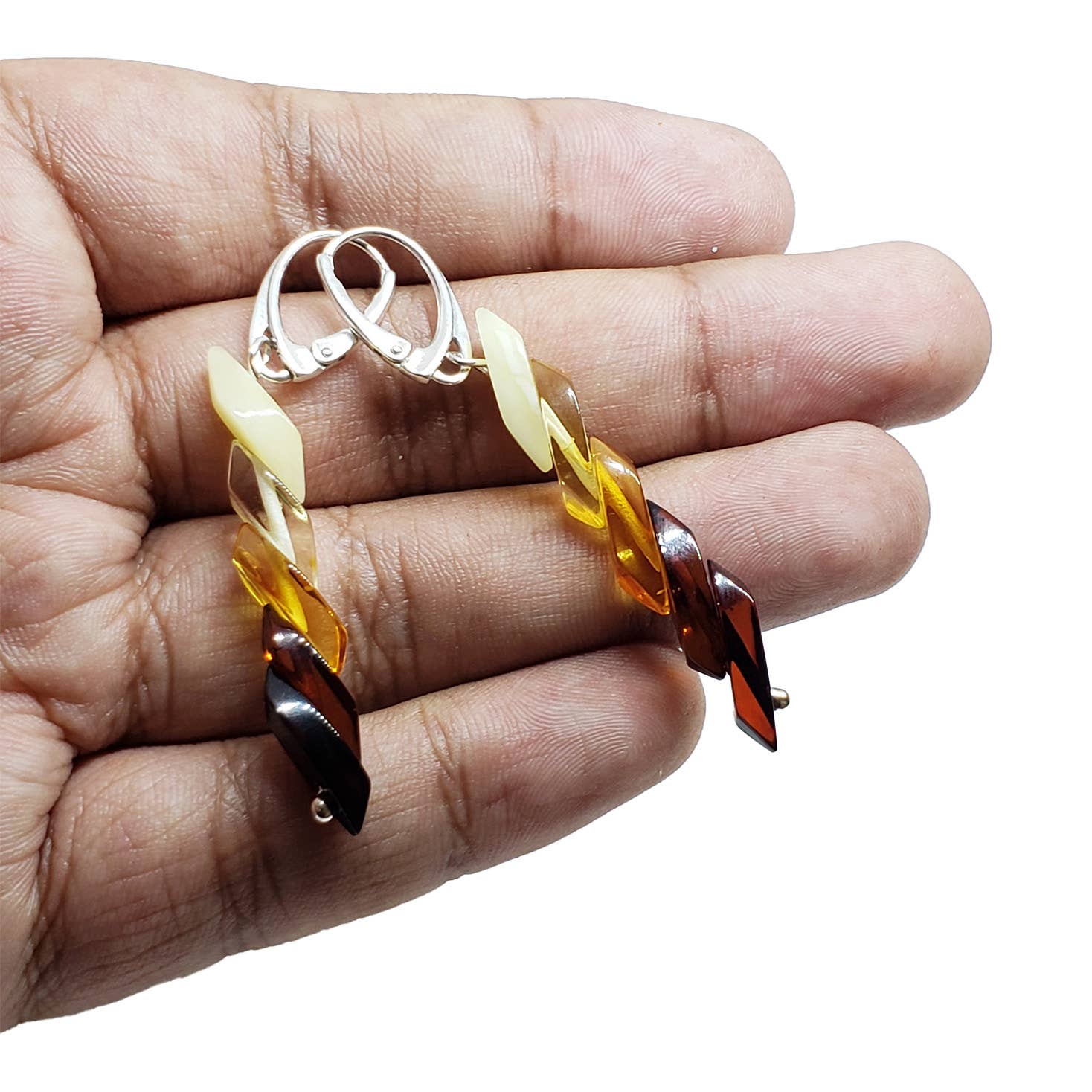 A person holds a pair of Multi-Color Genuine Baltic Amber Rainbow Earrings with metal clasps, highlighting the enchanting allure of amber jewelry.