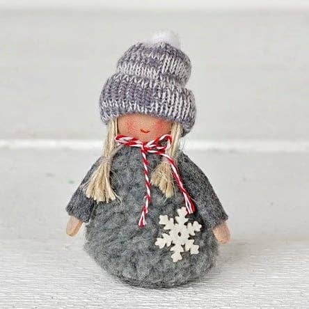 Gnome ornament wearing a grey knit sweater and matching beanie with a white wooden snowflake.