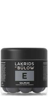 A jar with a black lid and black label displaying “Lakrids by Bülow E Salmiak,” containing round Nordic candy pieces.