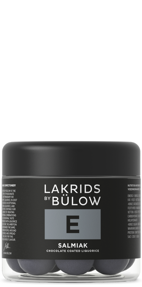 A jar with a black lid and black label displaying “Lakrids by Bülow E Salmiak,” containing round Nordic candy pieces.