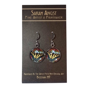 These handmade Swallowtail Butterfly earrings by Sarah Angst showcase intricate stained glass butterfly designs. Crafted with meticulous attention to detail, they come displayed on a card labeled "Sarah Angst Art, Fine Artist & Printmaker," capturing the essence of unique artistry from Bozeman, MT.