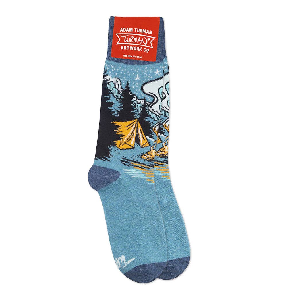 Socks: Campfire Socks - One Size by Adam Turman are unisex blue socks with a camping scene—tents, trees, campfire, and starry sky. The label reads Adam Turman Artwork Co. One size fits most.