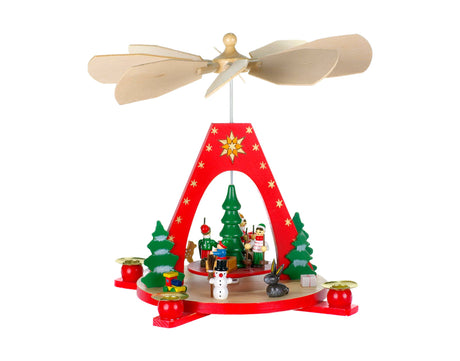 A wooden Christmas pyramid named "Red Pyramid W/Playing Children" features spinning blades and displays charming figures of Santa, a snowman, and festive trees. Its golden candle holders paired with red candles add warmth to its enchanting appeal.