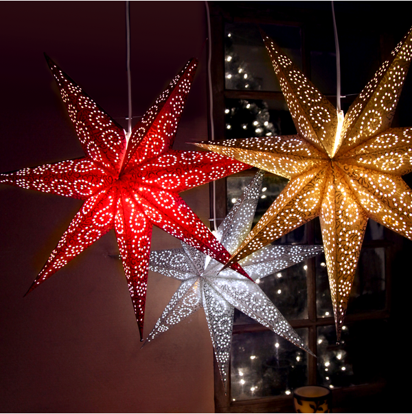 Three white antique hanging star candelabras from Star Trading illuminate a dim room, with a window showing a blurred view of lights outside.