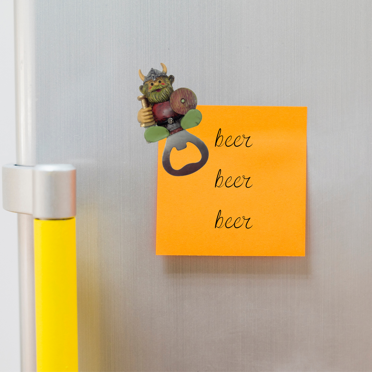 The Magnet: Norwegian Viking Refrigerator Magnet Bottle Opener is attached to a fridge, holding an orange sticky note with “beer beer beer” in cursive—a playful and functional addition to your kitchen decor.