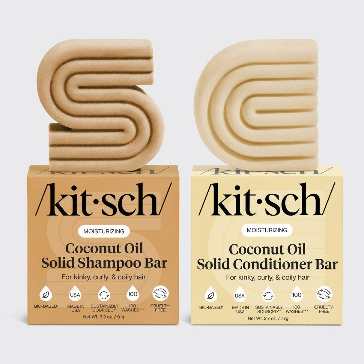 Two beige solid bars, shaped as S and D, sit atop boxes labeled "Hair: Coconut Oil Shampoo & Conditioner Bar Combo for Dry Damaged Hair 2 2.7oz Bars by Kitsch.