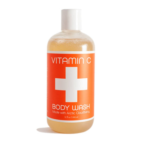 A 12 oz clear plastic bottle of Soap: Vitamin C Body Wash Nordic + Wellness, featuring an orange label with a white cross and text highlighting Arctic cloudberry oil and Organic Aloe Vera Juice.