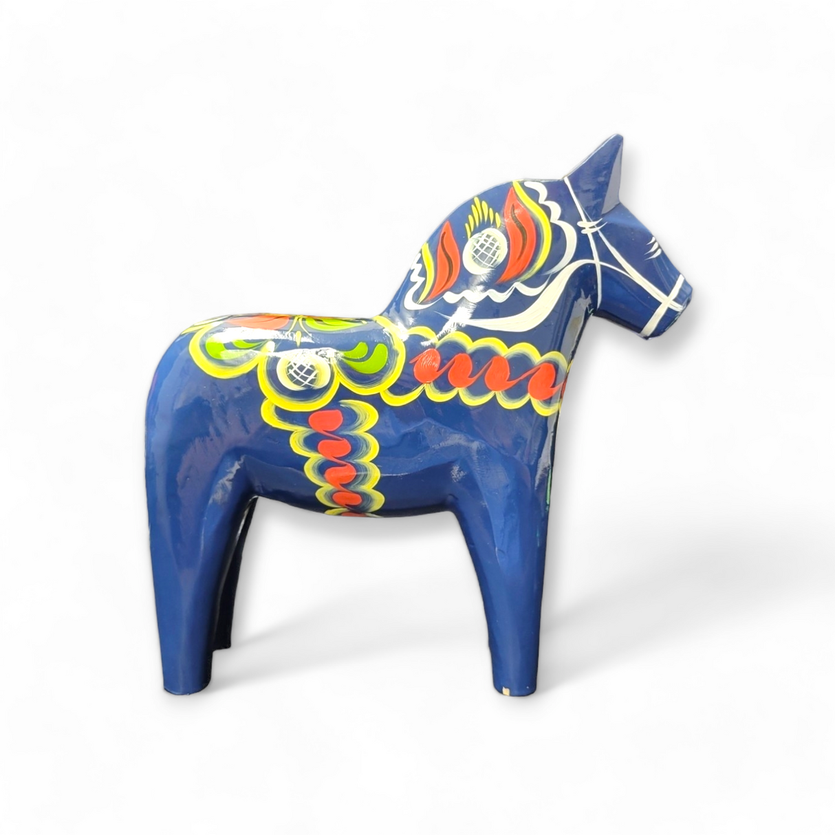A vibrant hand-carved Dala horse in blue adorned with intricate kurbits patterns on a blue background.