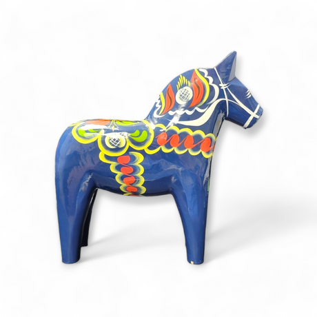 A vibrant hand-carved Dala horse in blue adorned with intricate kurbits patterns on a blue background.