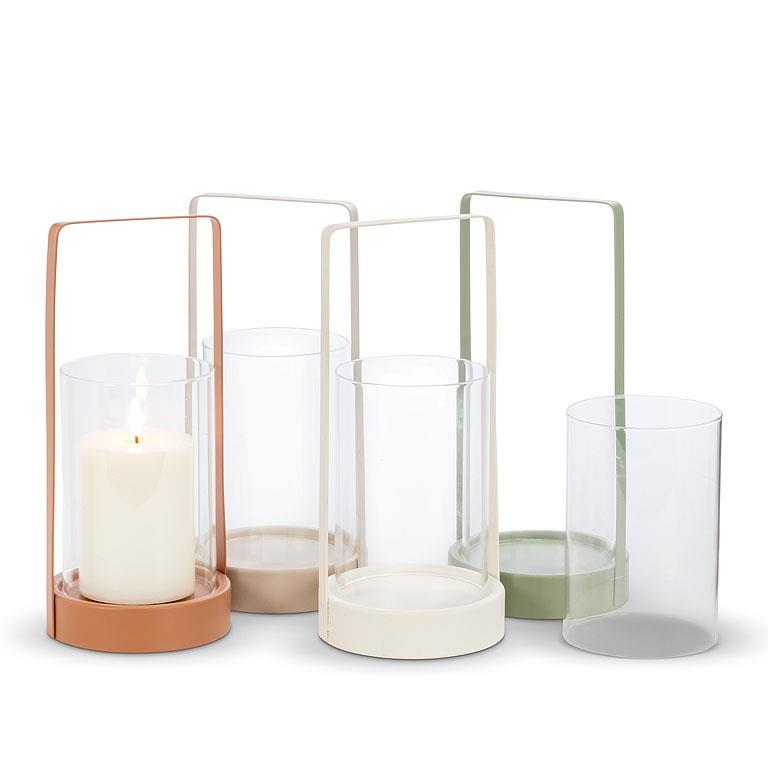 Four 10.5" Cylinder Lantern glass candle holders with metal bases in various colors, including one holding a lit white candle, create delightful outdoor decor accents.