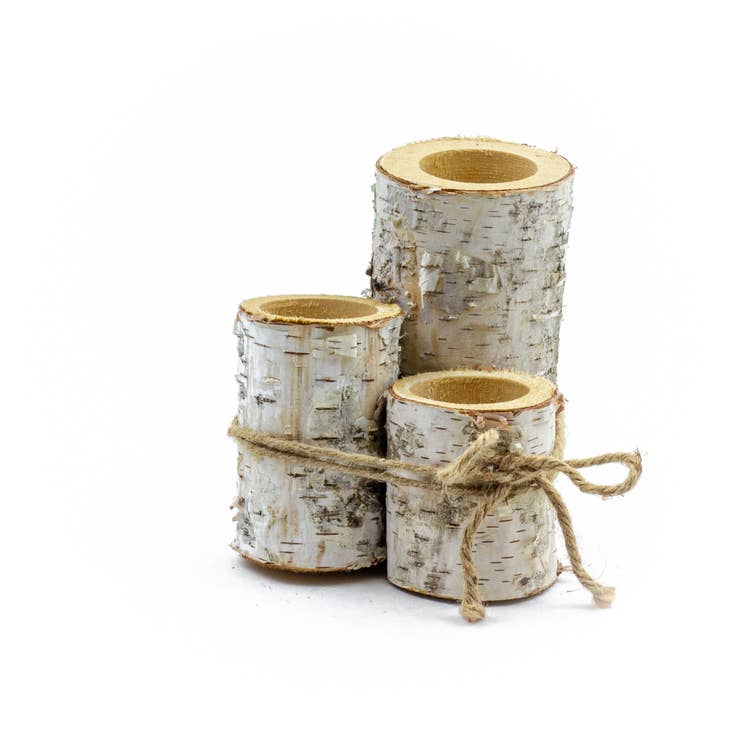 The Birch Decor Holder Set includes three candle holders made of birch wood, featuring a natural decor style with varying heights, and are bound together with twine against a white background.