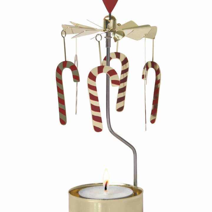 The Candle Holder: Candy Cane Red & White Rotary Candle Holder spins gracefully above a lit candle, adorned with candy cane decorations. This delightful carousel adds whimsical charm to any setting.