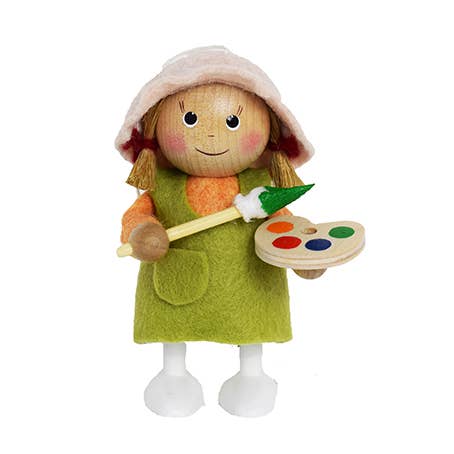 The Scandinavian Girl Artist Figurine wears a green apron and holds a paintbrush with a wooden palette.