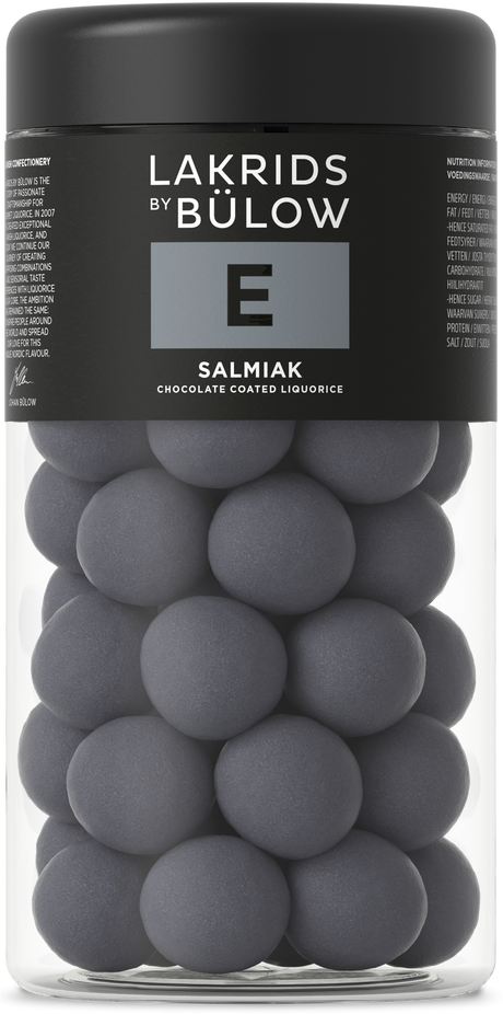 A clear jar with a black lid and gray front label contains round, dark gray chocolate-coated licorice candies. The Nordic brand name is visible on the label.