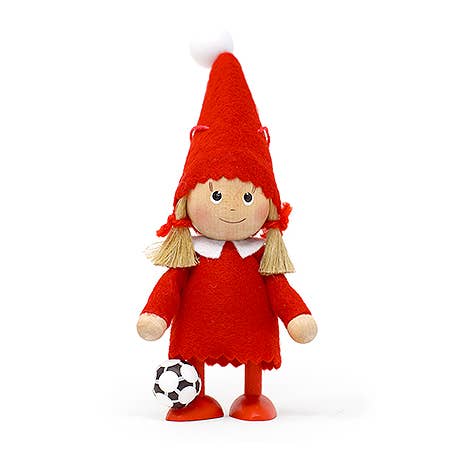 The Figurine: Scandinavian Girl with Soccer Ball is a charming wooden doll wearing a red hat and dress, playfully standing with a small soccer ball at its feet.