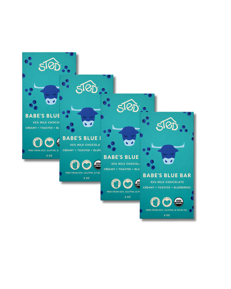 Four blue chocolate bar packages featuring wild blueberries and cow illustrations, arranged in a staggered row on a white background.
