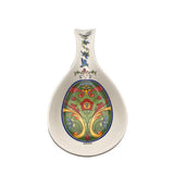 Add Scandinavian charm to your kitchen with the Green Norwegian Rosemaling Ceramic Spoon Rest, featuring colorful floral and scroll patterns in green, red, yellow, and blue on a white background.