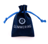A small navy blue drawstring pouch with "GLIMMERING" and a circular logo in white—perfect for gifting Earrings: April Crystal Swarovski® Crystals Spiral Dangle Earrings.