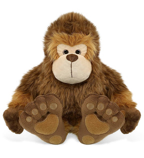 The Plush: Super-Soft Big Foot Stuffed Plush features brown fur, a beige face, and large embroidered feet, sitting upright and facing forward to resemble a charming stuffed Bigfoot cryptid plush toy.