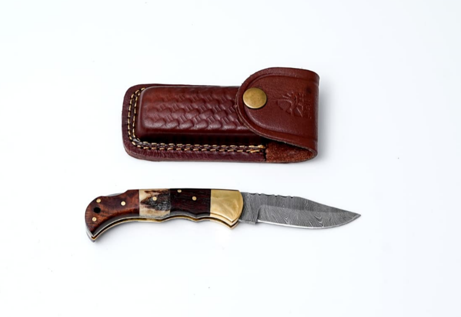 The Knife: Pocket Knife Walnut Wood & Stag 6.5'' Damascus Steel, featuring a patterned blade and walnut wood handle, is displayed beside a brown leather sheath on a white background.