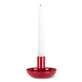 A white taper candle glows in the Small Pipe Taper Holder-Red (2"H), adding striking modern table decor to any plain white background.