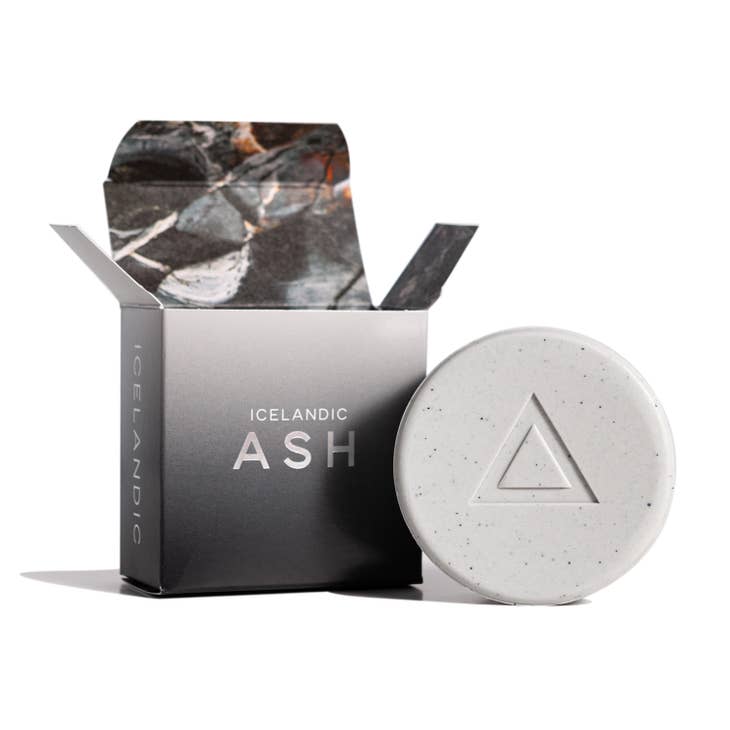 A circular soap bar featuring a triangle design sits next to an open box labeled "Hallo Iceland Ash Soap," promising detoxifying exfoliation.