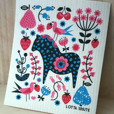A decorative dish cloth featuring a blue and black Swedish Dala Horse amid stylized flowers, birds, strawberries, and cherries, designed by Swedish artist Lotta Spjute.