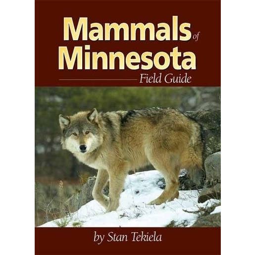 Cover of the book "Mammals of Minnesota Field Guide" by Stan Tekiela, showcasing mammal identification with an image featuring a wolf standing on snowy terrain with a forest in the background.