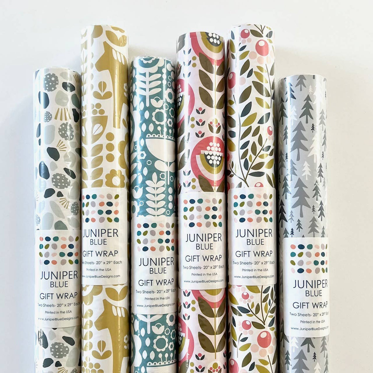 Two glossy sheets of Juniper Blue’s Swedish Dala Horse gift wrap (20" x 29" each) display vibrant designs featuring traditional motifs in rich colors, perfect for adding a festive Scandinavian touch to your presents.