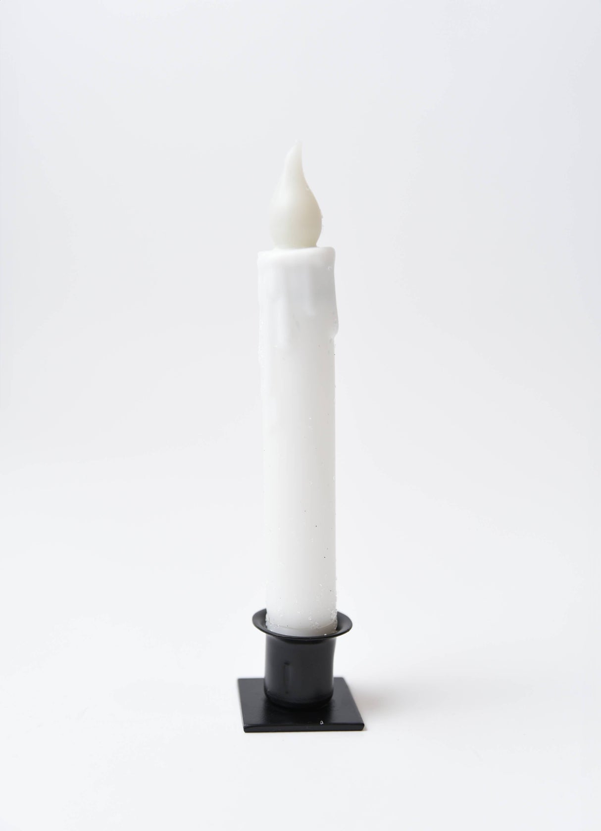 The Candle: Diamond Dusted Christmas LED Timer Taper Candle features melted wax drips and stands upright in a black square holder against a plain white background.