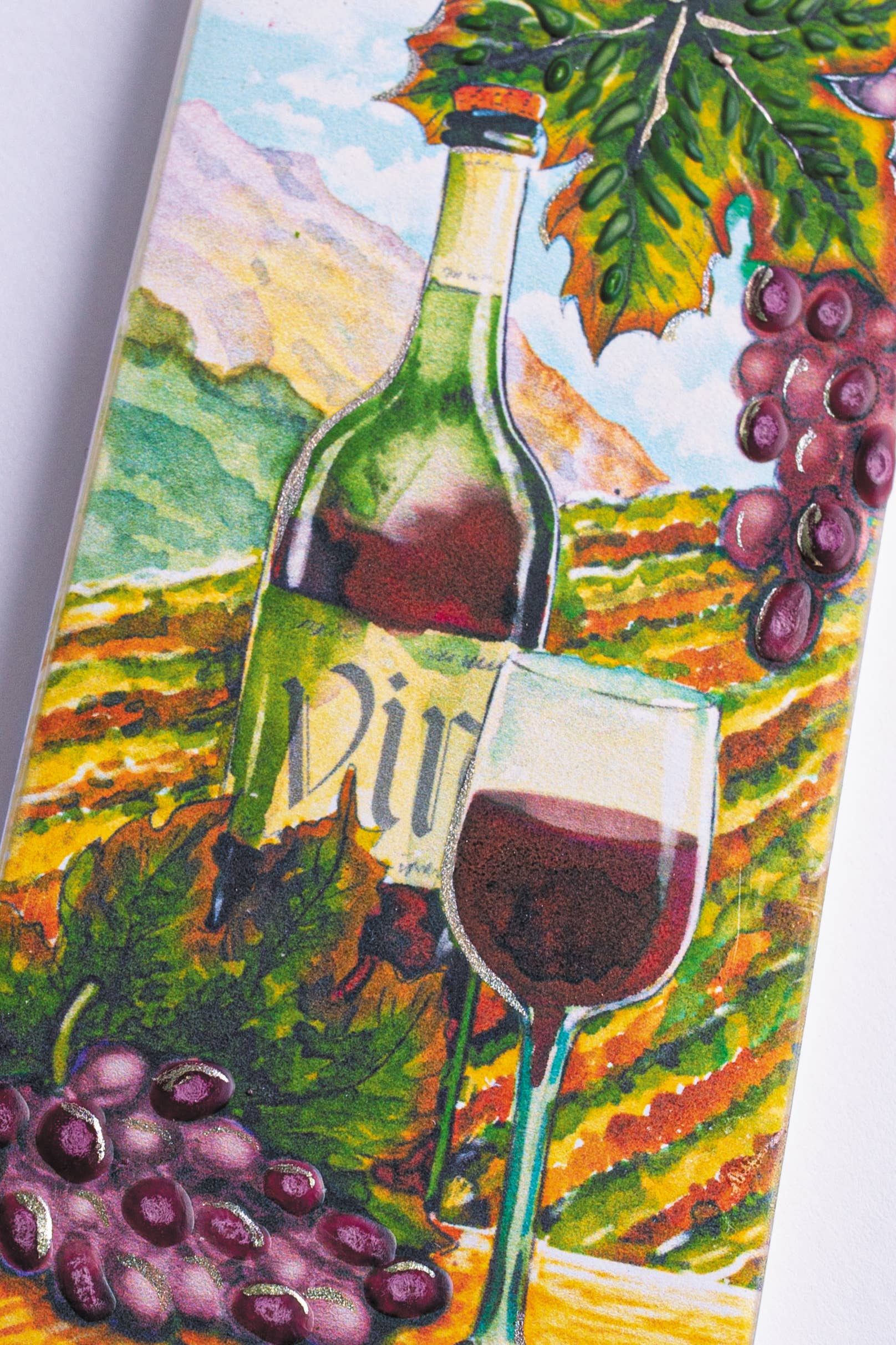 A hand-crafted depiction featuring a wine bottle, a glass of red wine, and grapes, artistically placed against a vineyard landscape with rolling hills.