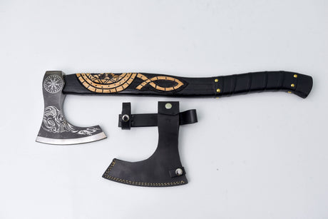 The Axe: Jörmungandr’s Grasp Camping Tool is a Viking-style hatchet with Norse engravings and a patterned handle, displayed with a black leather sheath on a light background.