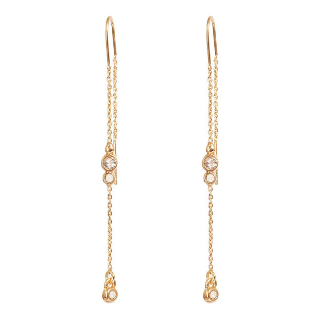 Earrings: A&C Oslo Long Crystal Chain Gold Earrings feature clear round gemstones and delicate gold chains with small dangling elements for a refined, organic look.