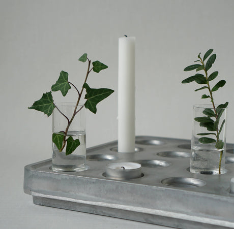 The Candle Holder: Mini Vases for Stumpastaken Candleholder 2-pack, with green leafy stems, pairs with a white pillar candle and tealight on a metal tray—an ideal table decoration against a light gray background.