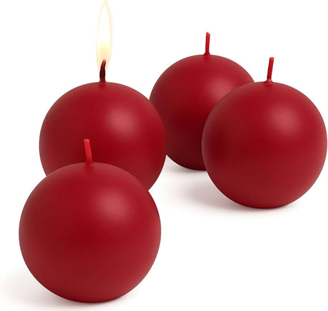 Four Cranberry Red Ball Candles (2.5" diameter) are shown, one lit and three unlit, creating a festive decorative accent for any space.