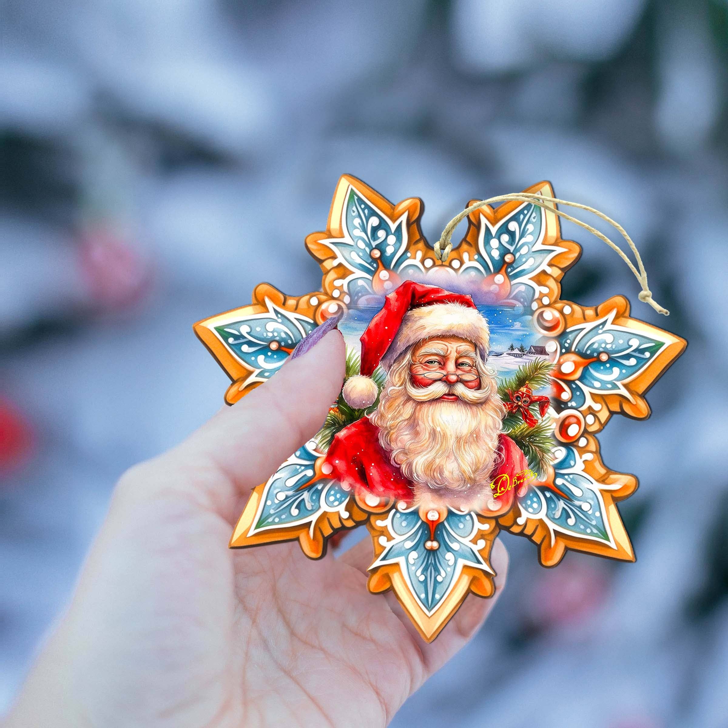 A hand holds the Ornament: Santa Snowflake Wood Ornaments GDebrekht, showcasing a joyful Santa Claus design against a blurred snowy background.