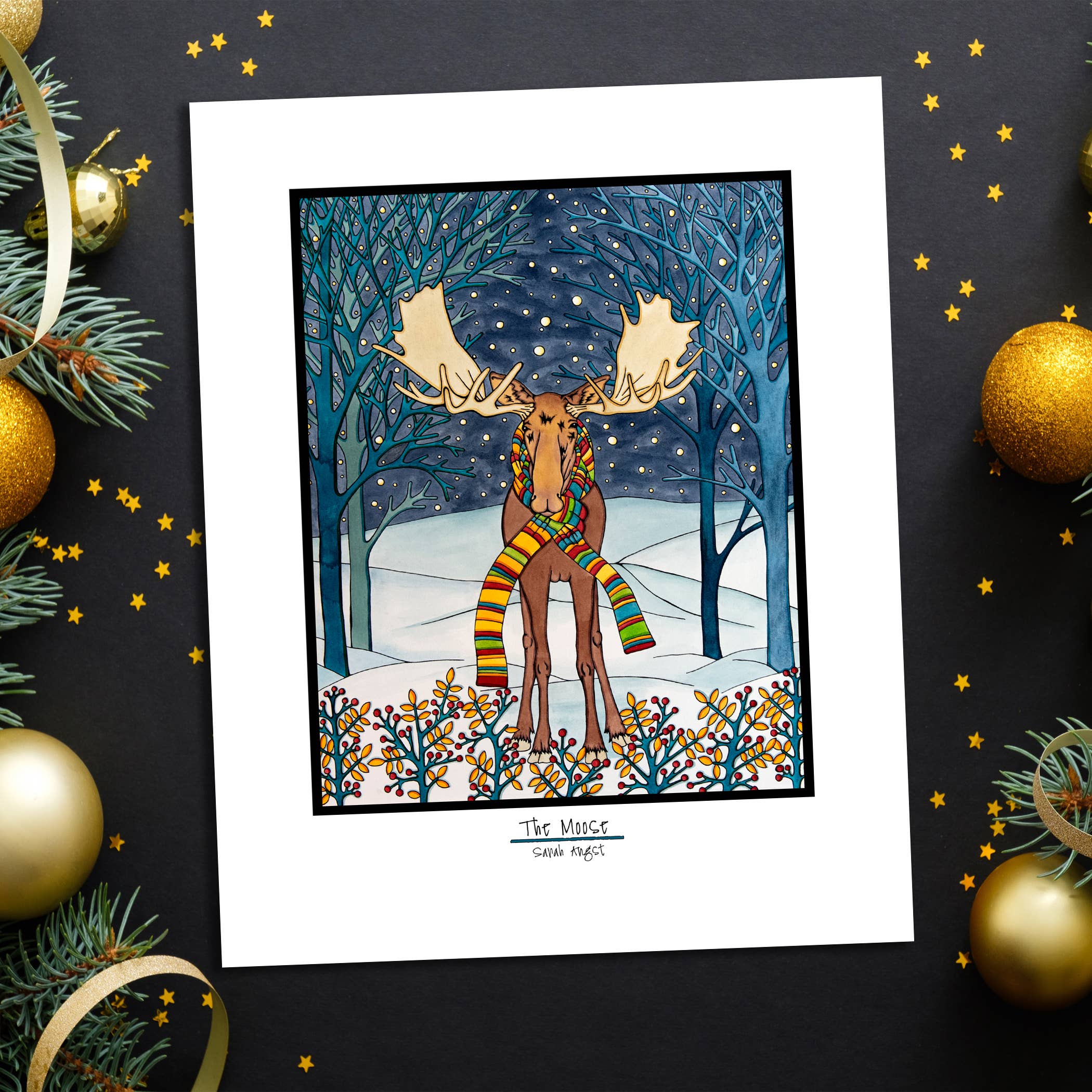 Artwork: Holiday Moose is an 11"x14" Giclee Print by Sarah Angst, featuring a moose in a colorful scarf amid a snowy, festive forest beneath a starry night sky.