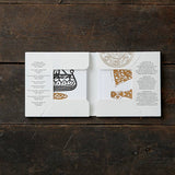 Open the Card Pack: Viking Finds Square Card Folder by Koustrup & Co - Denmark on a wooden surface to reveal intricate black and white Viking motifs with gold accents inside.