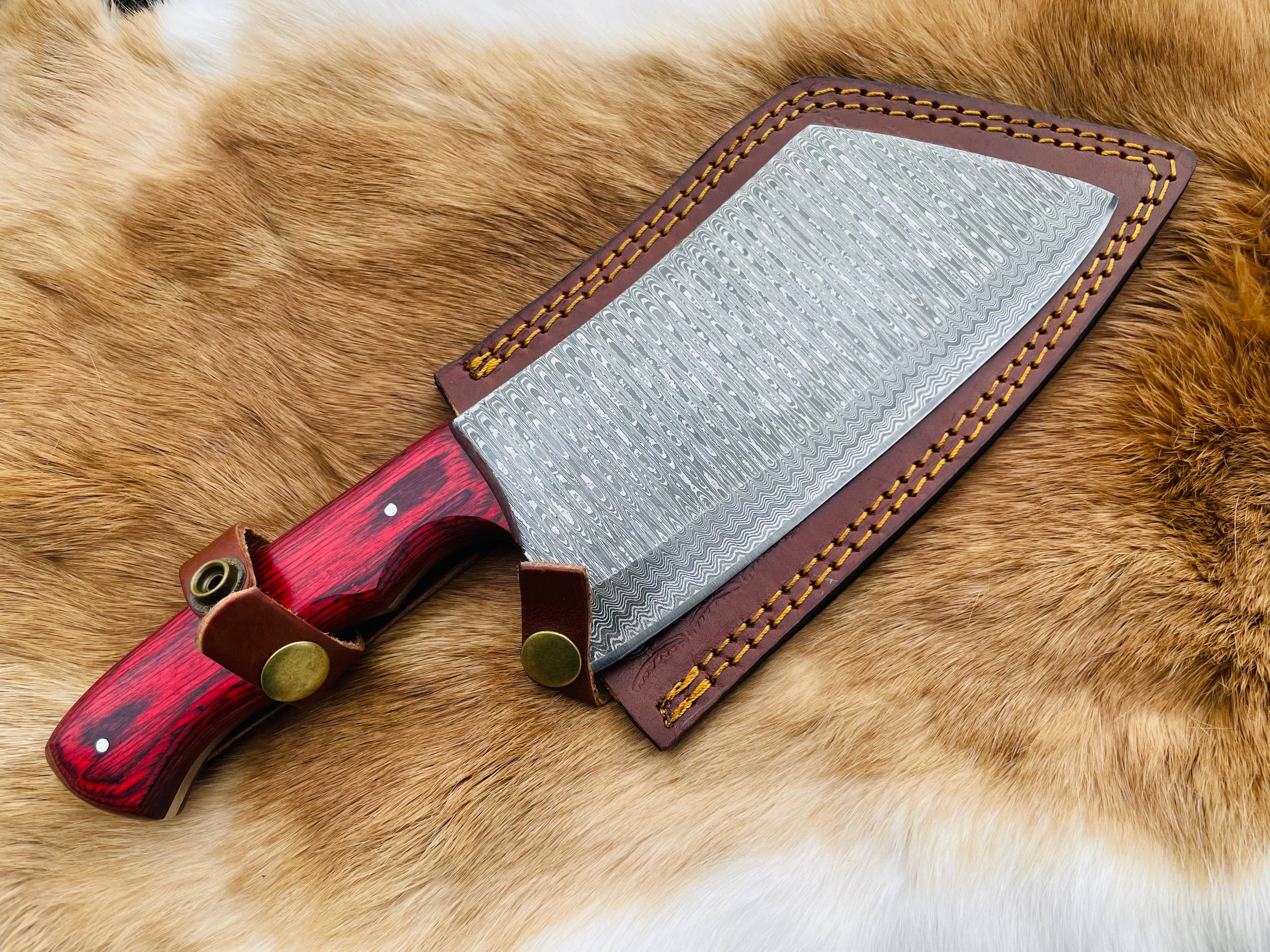 The Knife: Custom Damascus Steel Cleaver Red Handle Chinese Cleaver features a striking patterned blade, red handle, and brown leather sheath, displayed on tan fur for a bold presentation.
