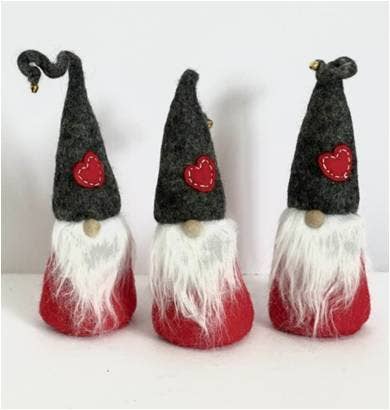 Three felt Tomte Scandinavian gnome figurines with gray hats, white beards, and red heart patches arranged in a row on a plain white background.